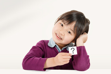 疑問、クエスチョンマークのカードを持つ小学生の女の子