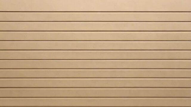 Close-up static shot of a tan horizontal siding, evenly spaced with distinct shadow lines creating a textured, structured facade