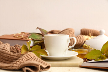 Composition with autumn leaves, cup of green tea and sweater on table near light wall, closeup