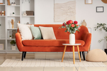 Comfortable sofa and coffee table with dahlia flowers in vase in living room
