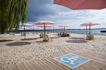 Wheelchair accessible rest area  for handicapped people on the public beach with the pink umbrellas
