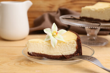 Glass plate with piece of sweet vanilla cheesecake on wooden background