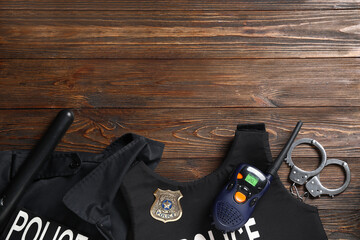 Police uniform, walkie-talkie and handcuffs on wooden background
