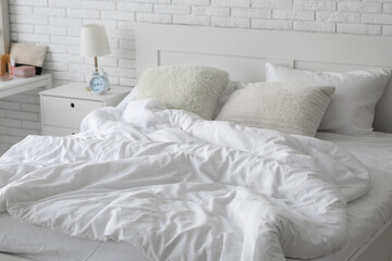 Cozy bed with soft pillows and white blanket in bedroom