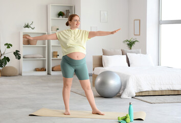 Fototapeta premium Sporty pregnant woman training in bedroom