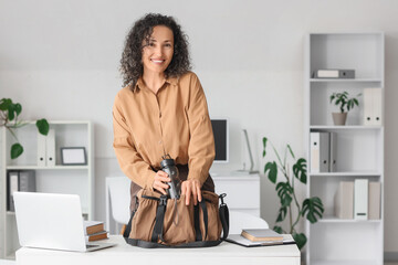 Mature businesswoman putting water bottle into sports bag at table in office
