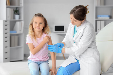 Fototapeta premium Female doctor vaccinating little girl in clinic