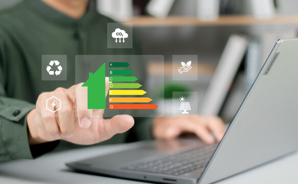 Hand of businessman using laptop with energy efficiency rating, Home improvement concept, ecological and bioenergetic house, efficiency scale.