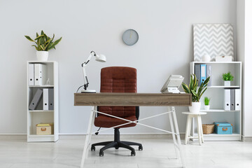 Modern workplace with telephone, lamp and sansevieria houseplants in office