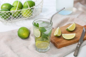 Glass of fresh Mojito cocktail with limes and mint on white background