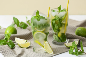 Glasses of fresh Mojito cocktail with limes and mint on white table