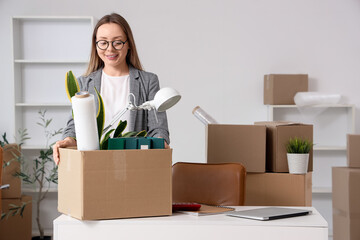 Young businesswoman packing things in office on moving day