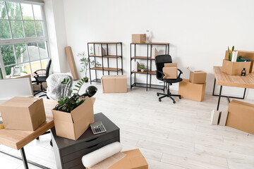 Interior of office with workplace, shelf units and cardboard boxes on moving day