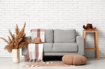 Interior of living room with stylish hats, sofa and stool