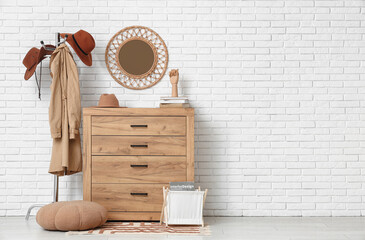 Interior of hallway with stylish hats, commode and coat rack