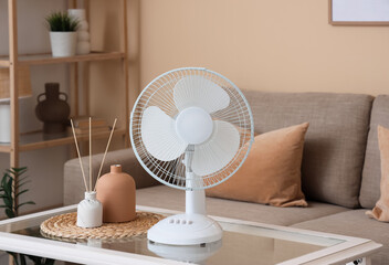 Electric fan on table near sofa in living room