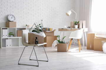 Interior of office with desk, chairs and cardboard boxes on moving day