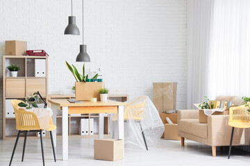 Interior of office with workplace, sofa and boxes on moving day
