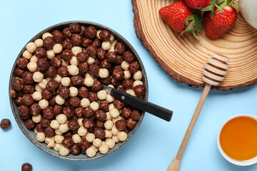 Round wood slice, strawberry and bowls with chocolate corn balls and honey on blue background