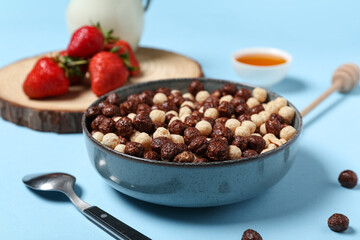 Bowl of chocolate corn balls on blue background, closeup