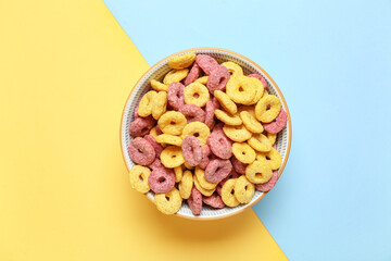 Bowl of tasty color cereal rings on color background, closeup