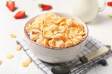 Composition with bowl of tasty cornflakes and napkin on white wooden background, closeup