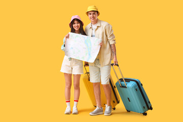 Couple of tourists with map and suitcases on yellow background