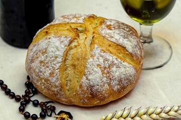 Catholic sacred table with rustic bread, olive oil, wine, grapes, rosary and ears of wheat. The body and blood of Christ
