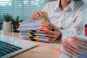 An office worker in a white shirt organizes a large stack of documents with colorful paper clips...