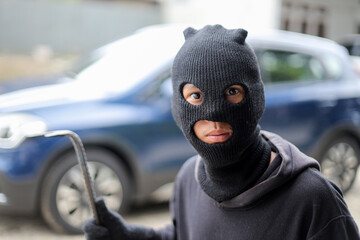 Thief in Black Balaclava Hold Metal Tools and Attempting to Steal Car from Residential Parking Area.