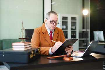 Mature Male judge in a courtroom on white table and Counselor or Male lawyer working in office. Justice and law concept