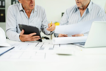Two colleagues discussing data working and tablet, laptop with architectural project at construction site at desk
