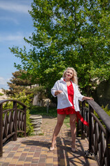 Blonde Woman Bridge: Woman poses on bridge for photo, daytime, outdoor nature scenery, enjoying sunny day.