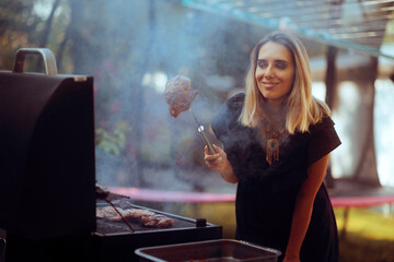 Woman Holding a Barbecue Meat with a Fork Making Lunch. Cheerful person is preparing a garden party in the summer 