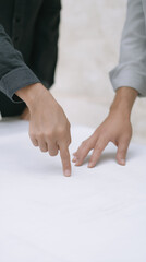 Two hands pointing at a blank surface, demonstrating collaboration and communication in a professional setting, with soft lighting and neutral background enhancing focus on interaction