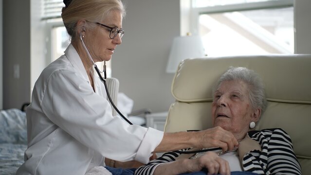 A healthcare professional conducts a wellness check on an elderly woman at home, ensuring her health needs are met. The setting is calm and supportive, fostering trust.