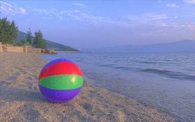 Obraz premium Colorful beach ball on sandy shore at sunrise