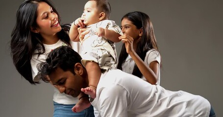 Father giving piggyback ride to infant as mother, daughter support him lovingly, enjoying quality family time indoors, isolated on gray background showing bonding and happiness together - Powered by Adobe
