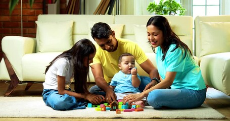 Indian infant playing with colorful wooden toys while sister, mother, father sit around on carpet in cozy modern living room, enjoying quality family time, laughter, bonding, happy parenting indoors - Powered by Adobe