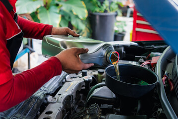Car mechanic drain the old lubricant engine oil at car garage for changing the oil in a car engine