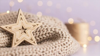 A charming wooden star rests gently on beige knitted blanket, creating cozy and festive atmosphere with soft bokeh lights shimmering in the background. - Powered by Adobe