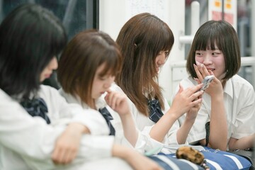 On a spring morning in the Shanghai subway, a group of Japanese high school girls in school uniforms sit on train seats, each quietly lost in her own thoughts during a calm commute in a foreign city.