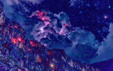 Dramatic night sky with stormy clouds over rocky peaks