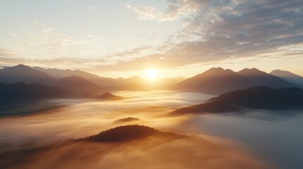 Fototapeta premium A breathtaking sunrise over misty mountain ranges with soft clouds and warm golden light illuminating the fog-covered valley below.