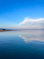 Evening calm and smooth lake surface under soft clouds