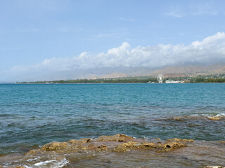 Rocky shore and clear water of Issyk-Kul under a vast sky