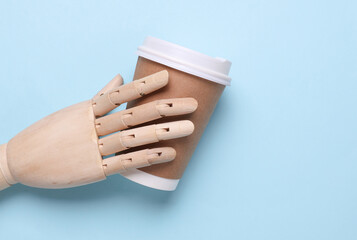 Wooden puppet hand holding a craft coffee cup. Eco concept