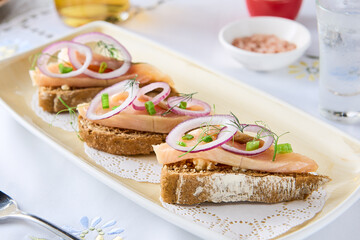 Herring toasts with onion, bright daylight, elongated overhead plate composition