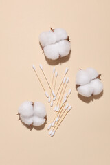 Cotton swabs and flowers on beige background. Personal hygiene
