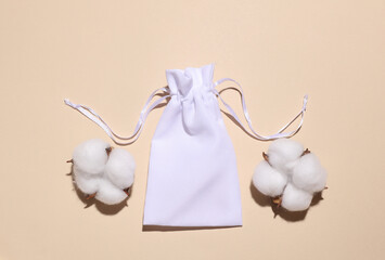 White bag and cotton flowers on beige background